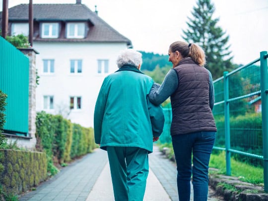 Eine Alltagsfee hilft einem Senior beim Spaziergang in Siegen.