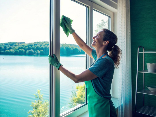 Lächelnde Alltagsfee wischt ein Fenster in einem Haus in Haltern am See.