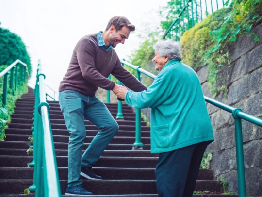 Eine Alltagsfee hilft einem Senior beim Treppensteigen in Hohenlimburg.
