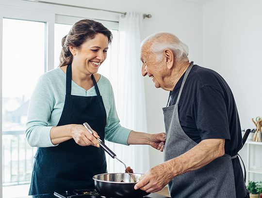Lächelnde Alltagsfee hilft Seniorin in Mechernich beim Kochen